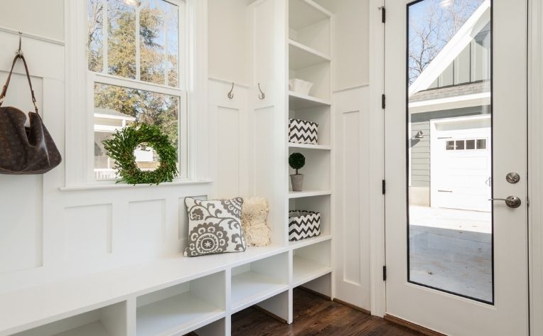 wood look flooring with white bench and storage in mudroom.